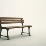 Eine schlichte Holzbank in einem leeren, hellen Raum - Symbol für das stille Gespräch mit dem Holocaust