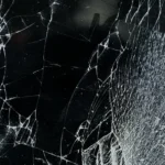 Nahaufnahme einer zerbrochenen Glasoberfläche mit feinen weißen Rissen als Symbol für zerfallende Illusionen