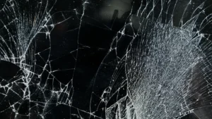 Nahaufnahme einer zerbrochenen Glasoberfläche mit feinen weißen Rissen als Symbol für zerfallende Illusionen