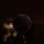 Nahaufnahme eines Mikrofons im Dunkeln - Symbol für Sprache, Stimme und öffentliche Debatte - und die Notwendigkeit für Präzision